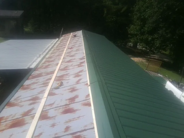 Old rusted panels beside newly installed green metal roofing — Wind Damage Roof Repair by Roofing Brothers in Edmond
