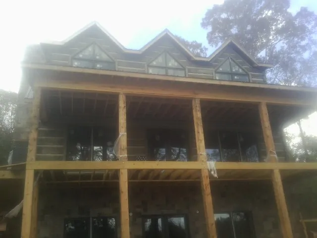 Dormers and porch framing on a large log home under construction — Roof Coating work by our crew in Edmond