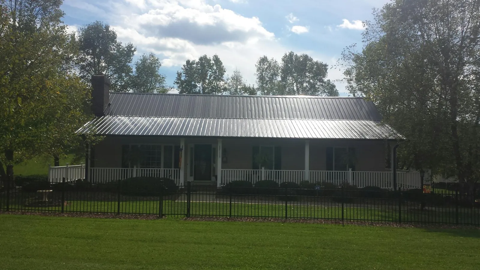 Gray metal roof on a brick ranch with a full width front porch — Gutter Guard Installation work by our crew in Edmond