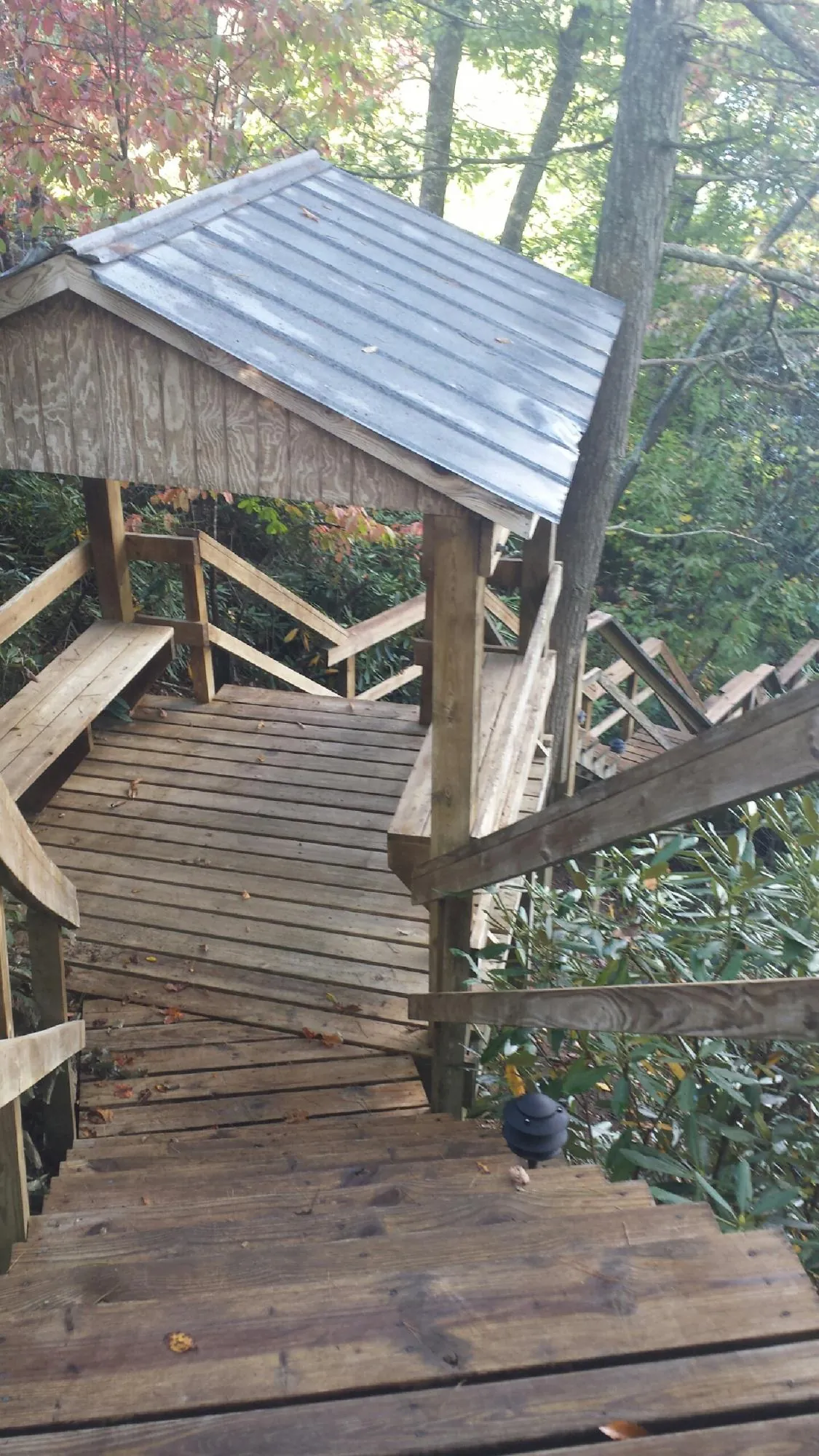 Metal roofed shelter over wooden steps on a wooded walkway — Skylight Repair & Installation work by our crew in Edmond