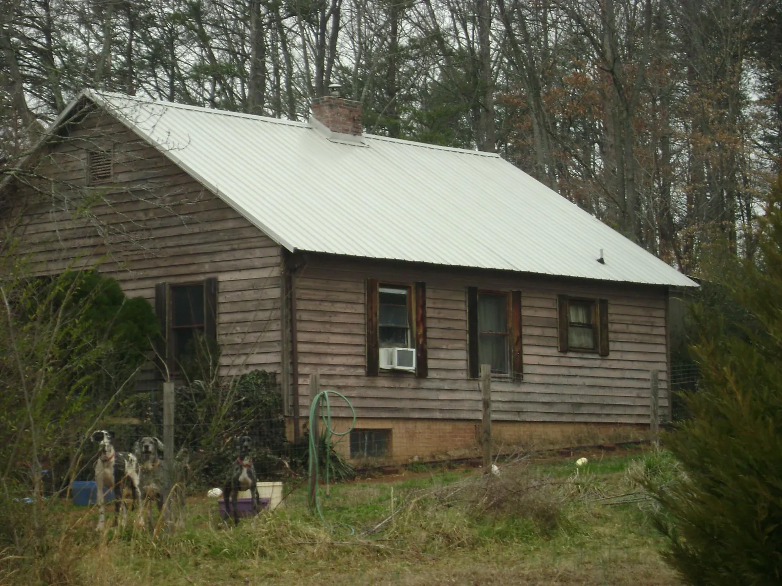 White metal roof on an old wood sided farmhouse, from a Asphalt Shingle Roof Repair job in Edmond