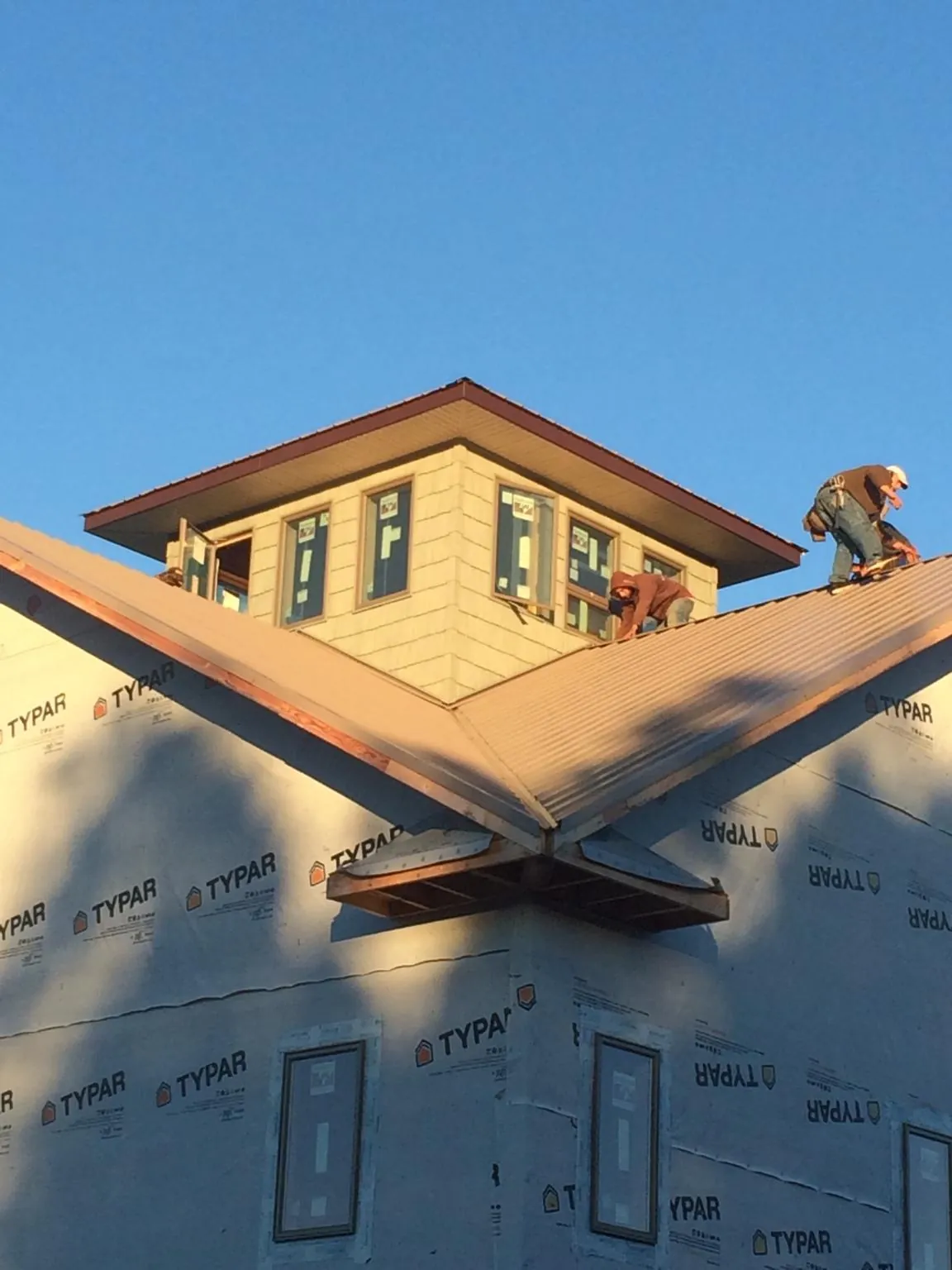 Roofers working around a rooftop cupola on a new metal roof at sunset — Roof Waterproofing in Edmond by Roofing Brothers